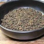Bol de grains de piment de la Jamaïque sur une table en bois, utilisé pour relever les plats culinaires.