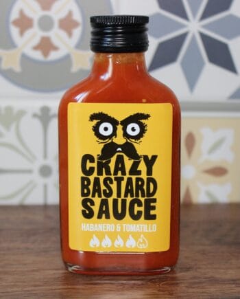 Sauce piquante Crazy Bastard au habanero et tomatillo, devant un fond de carreaux colorés.