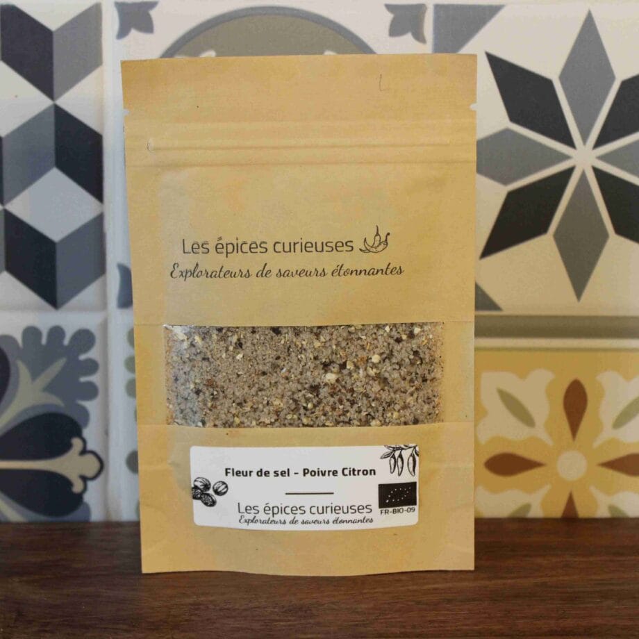 Sachet d'épices biologiques Les épices curieuses contenant fleur de sel et poivre citron, sur un fond de tuiles colorées.