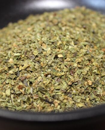 Herbes sèches dans un bol noir, idéales pour assaisonner vos plats et rehausser les saveurs de la cuisine méditerranéenne.