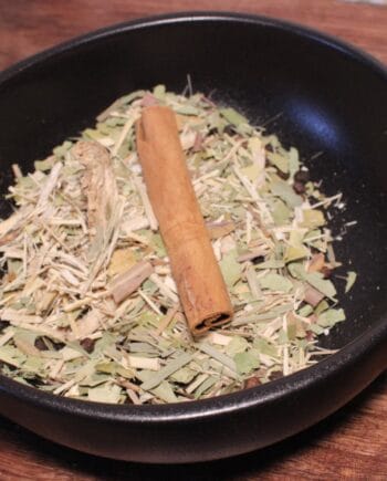 Bol d'herbes séchées et de cannelle, prêt pour infusion ou décoction aromatique.