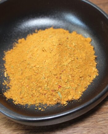 Bol de curry en poudre épicé sur une table en bois, idéal pour relever vos plats de cuisine maison.