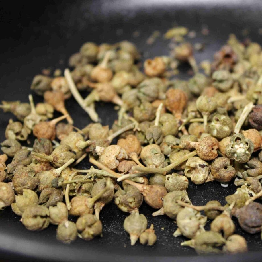 Baies séchées de poivre de Sichuan sur fond sombre, utilisées pour la cuisine asiatique et leurs propriétés uniques.