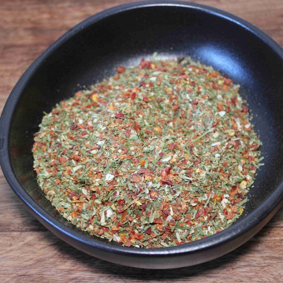 Assaisonnement aux herbes et épices dans un bol noir sur une table en bois