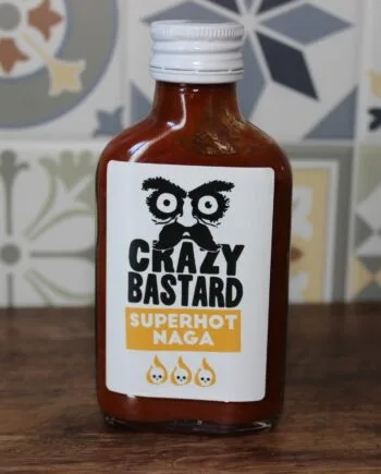 Bouteille de sauce piquante Crazy Bastard Superhot Naga sur fond de carrelage coloré.