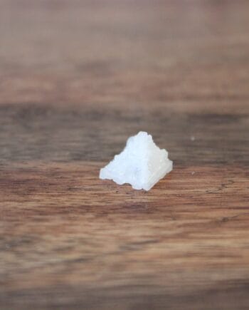 Cristal de sel en forme de pyramide sur une table en bois.