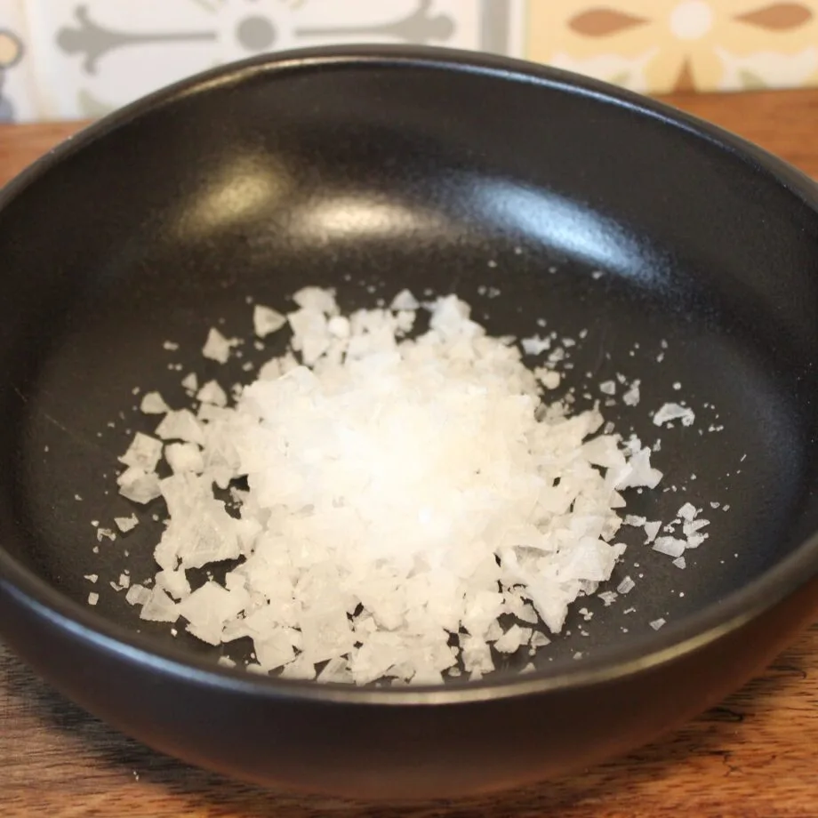 Flocons de sel de mer dans un bol noir parfaits pour relever vos plats gourmet
