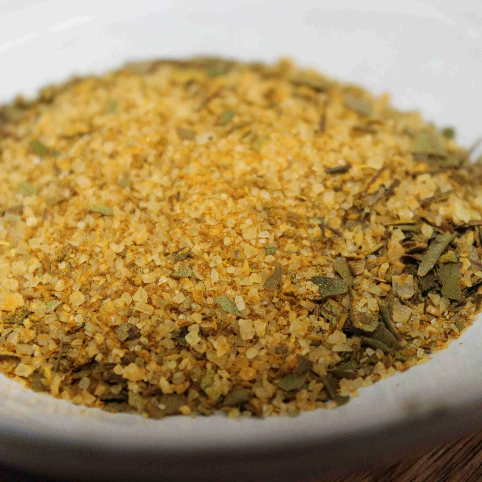 Mélange d'épices dorées sur une assiette blanche, idéal pour assaisonner vos plats.