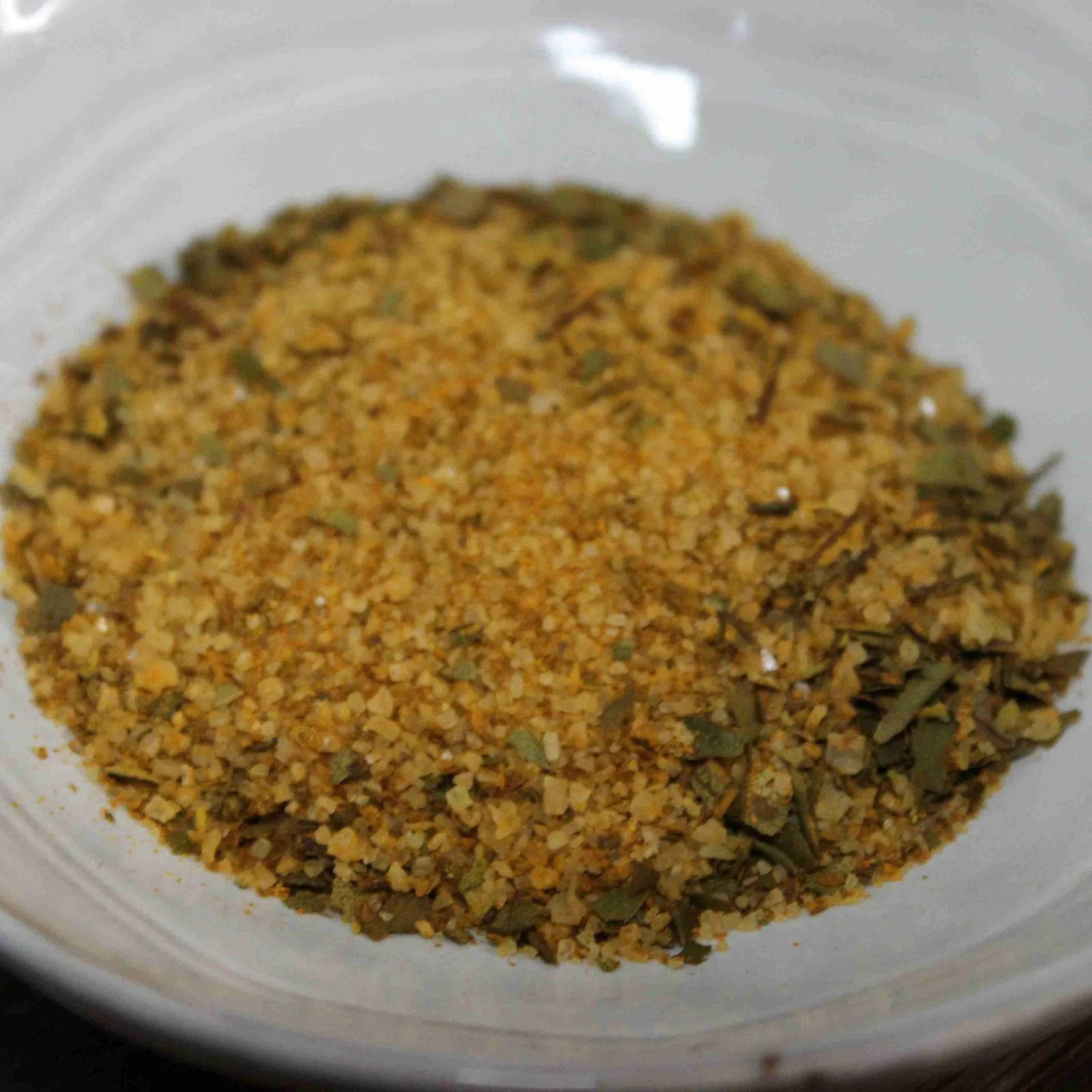 Mélange d'épices aromatiques dans un bol blanc, idéal pour assaisonner vos plats avec saveur et couleur.