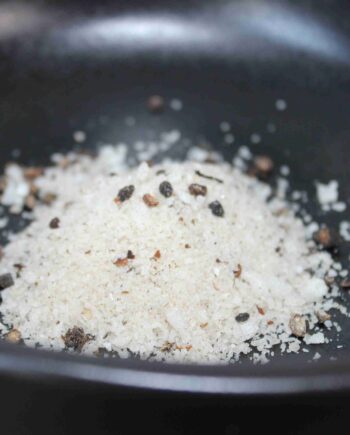 Sel assaisonné avec poivre et épices dans un bol noir, prêt à être utilisé en cuisine.