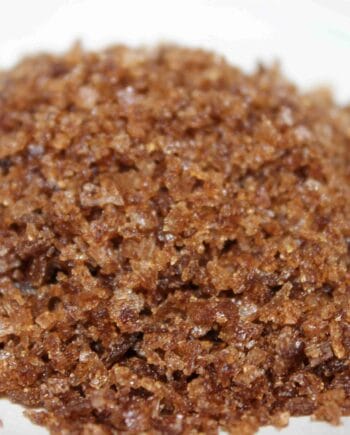 Gros plan sur du sucre brun naturel en grains, texture cristalline pour pâtisserie ou cuisine raffinée.