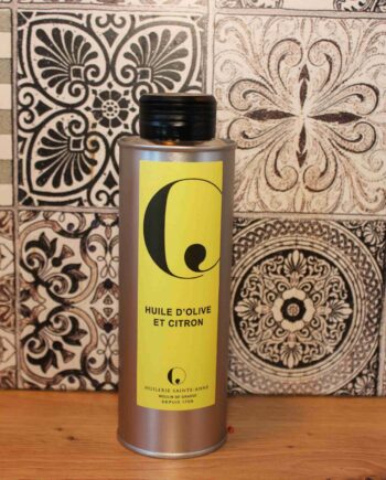 Bouteille d'huile d'olive et citron devant des carreaux décoratifs en noir et blanc.