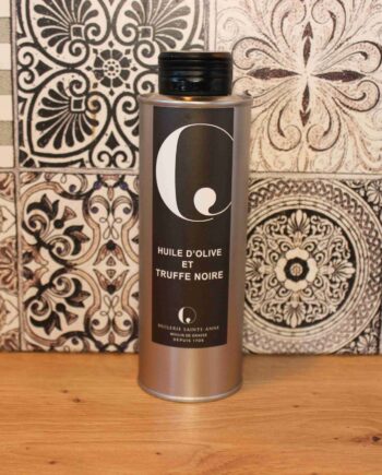 Bouteille d'huile d'olive à la truffe noire sur un fond de carreaux décoratifs.