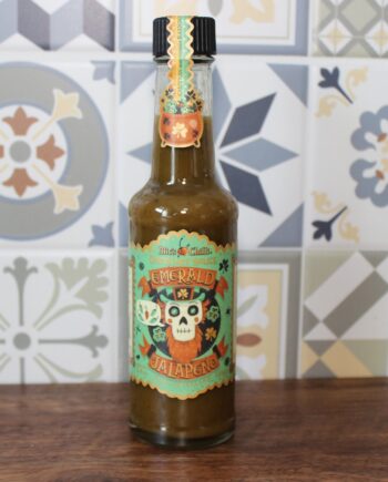 Bouteille de sauce piquante jalapeño Emerald, fond de carreaux colorés, design mexicain vibrant.