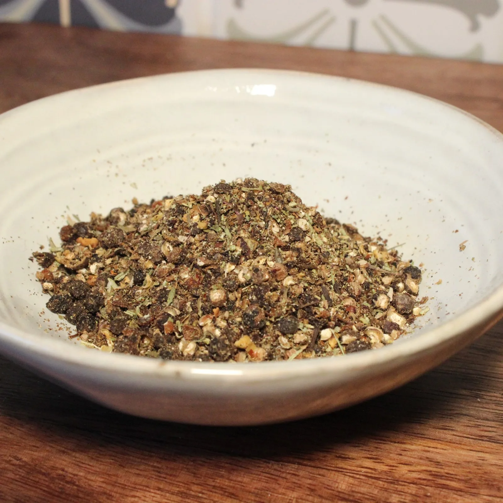 Assiette de mélange d'épices artisanales sur une table en bois pour une cuisine savoureuse et aromatique.