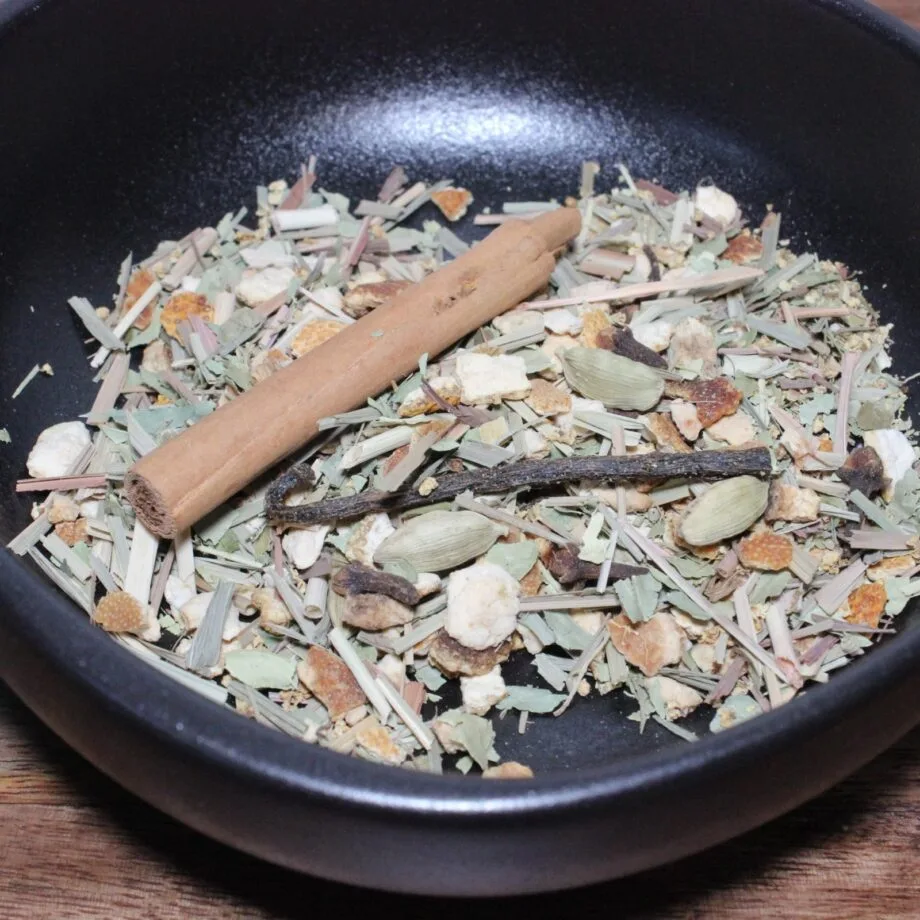 Mélange dépices séchées dans un bol noir avec bâton de cannelle et cardamome pour infusion parfumée