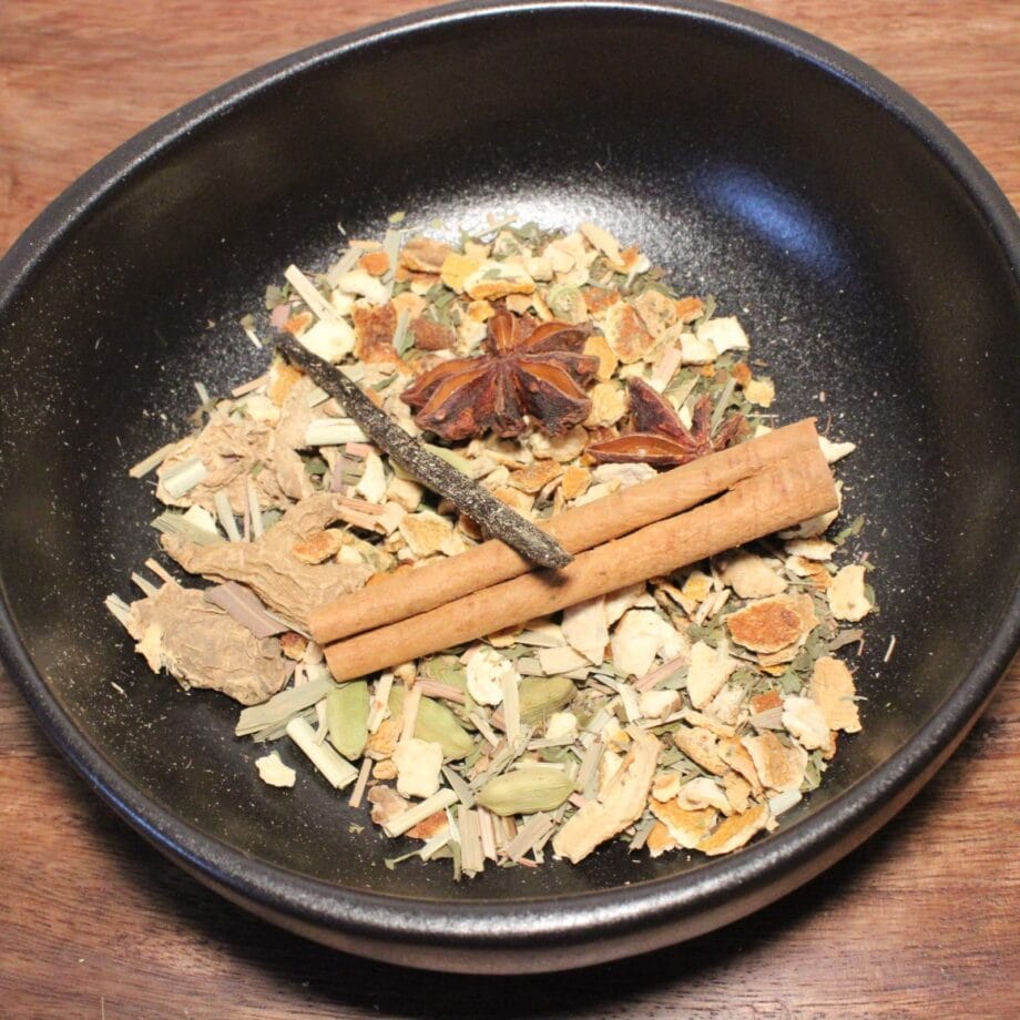 Mélange dépices variées dans un bol noir incluant cannelle et anis étoilé sur fond de table en bois