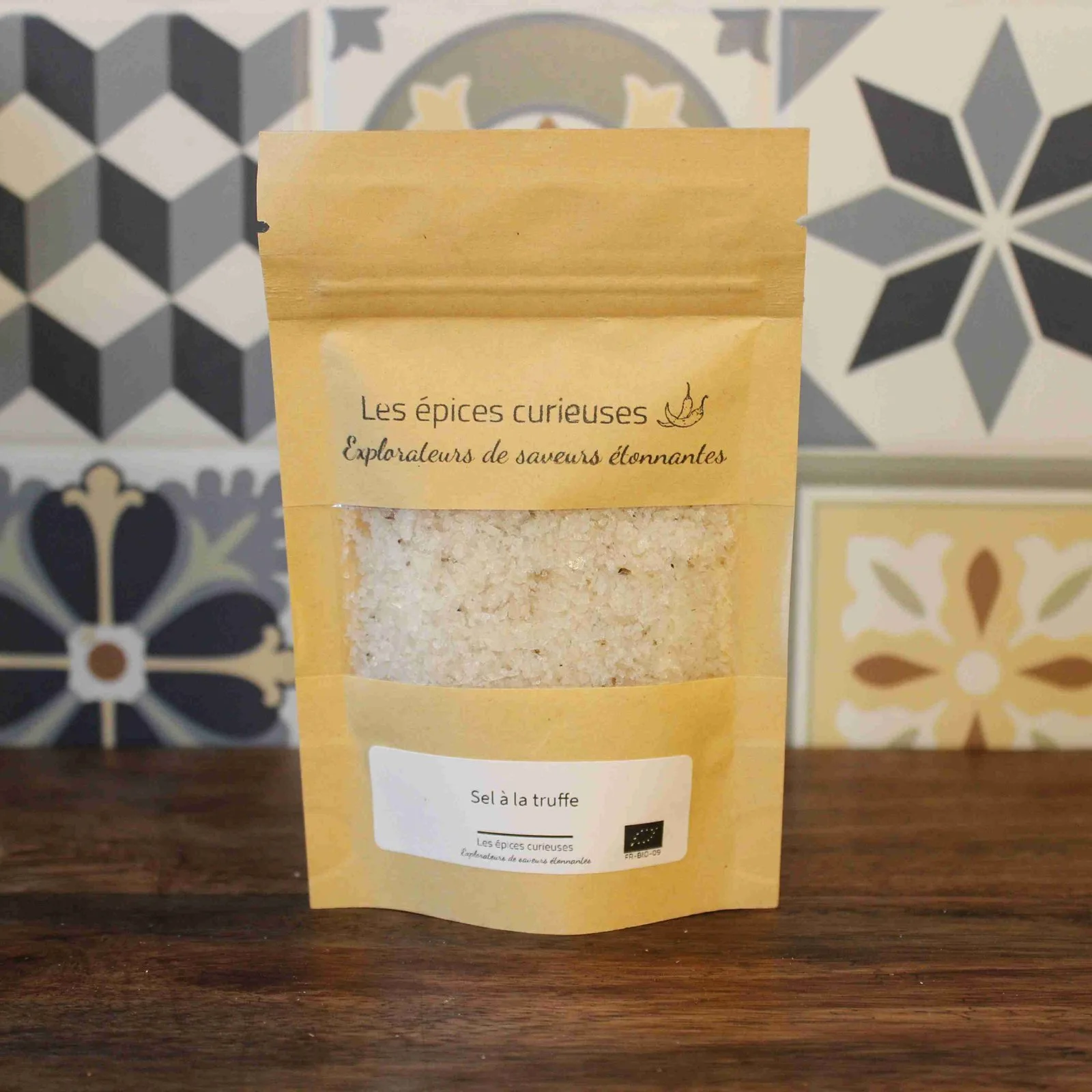 Paquet de sel à la truffe Les épices curieuses devant un fond de carreaux décoratifs.