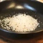 Sel de mer gourmet dans un bol noir, prêt à enrichir vos plats de sa saveur unique et délicate.