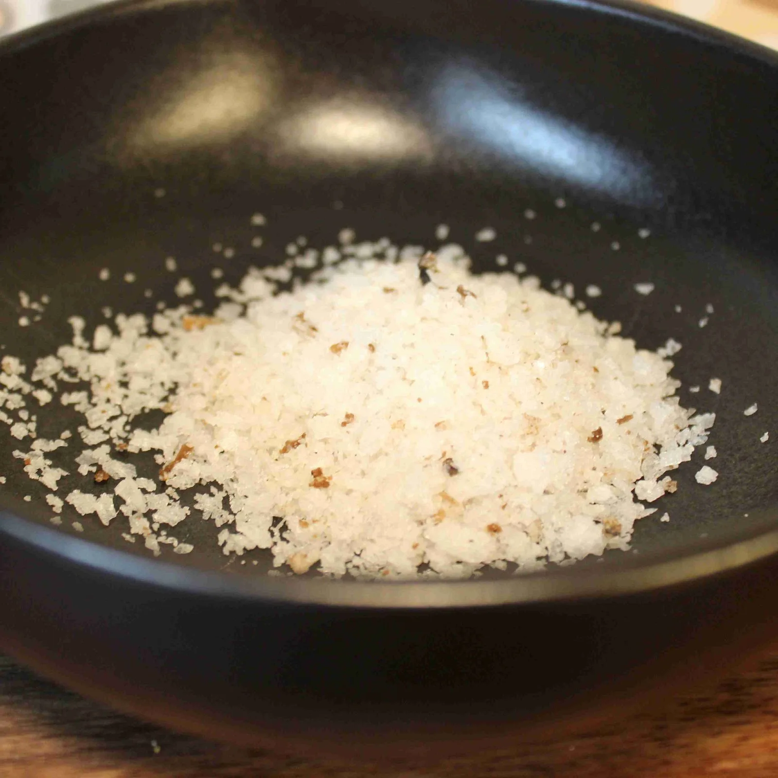 Sel de mer gourmet dans un bol noir, prêt à enrichir vos plats de sa saveur unique et délicate.