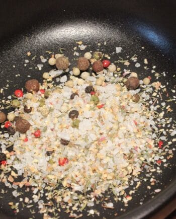 Mélange d'épices et de sel dans une poêle noire pour rehausser vos plats avec saveurs et arômes.