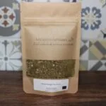 Mélange d'épices houmous par Les Épices Curieuses dans un sachet kraft, devant un fond décoratif.