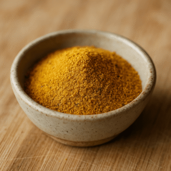 Bol de poudre de curry jaune sur planche en bois, épice exotique pour plats savoureux.