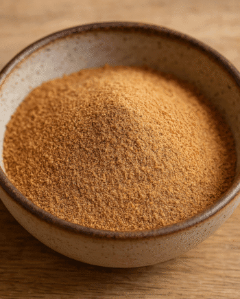 Bol en céramique rempli de poudre de sucre de coco sur une table en bois.