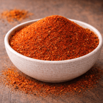 Bol de piment de Cayenne moulu, épice rouge vif sur une table en bois, idéal pour rehausser la saveur des plats.