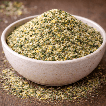 Bol rempli de gomasio aux graines de sésame et épices sur une table en bois.