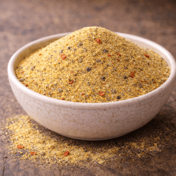 Bol de semoule épicée sur table rustique, parfait pour assaisonnement ou cuisine créative.