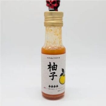 Petite bouteille de sauce au yuzu avec étiquette japonaise, bouchon doré et image d'un citron.