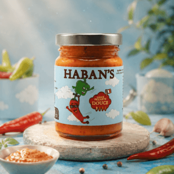 Pot de sauce piquante douce Haban's sur fond coloré, entouré de piments et d'épices. Idéal pour sublimer vos plats.